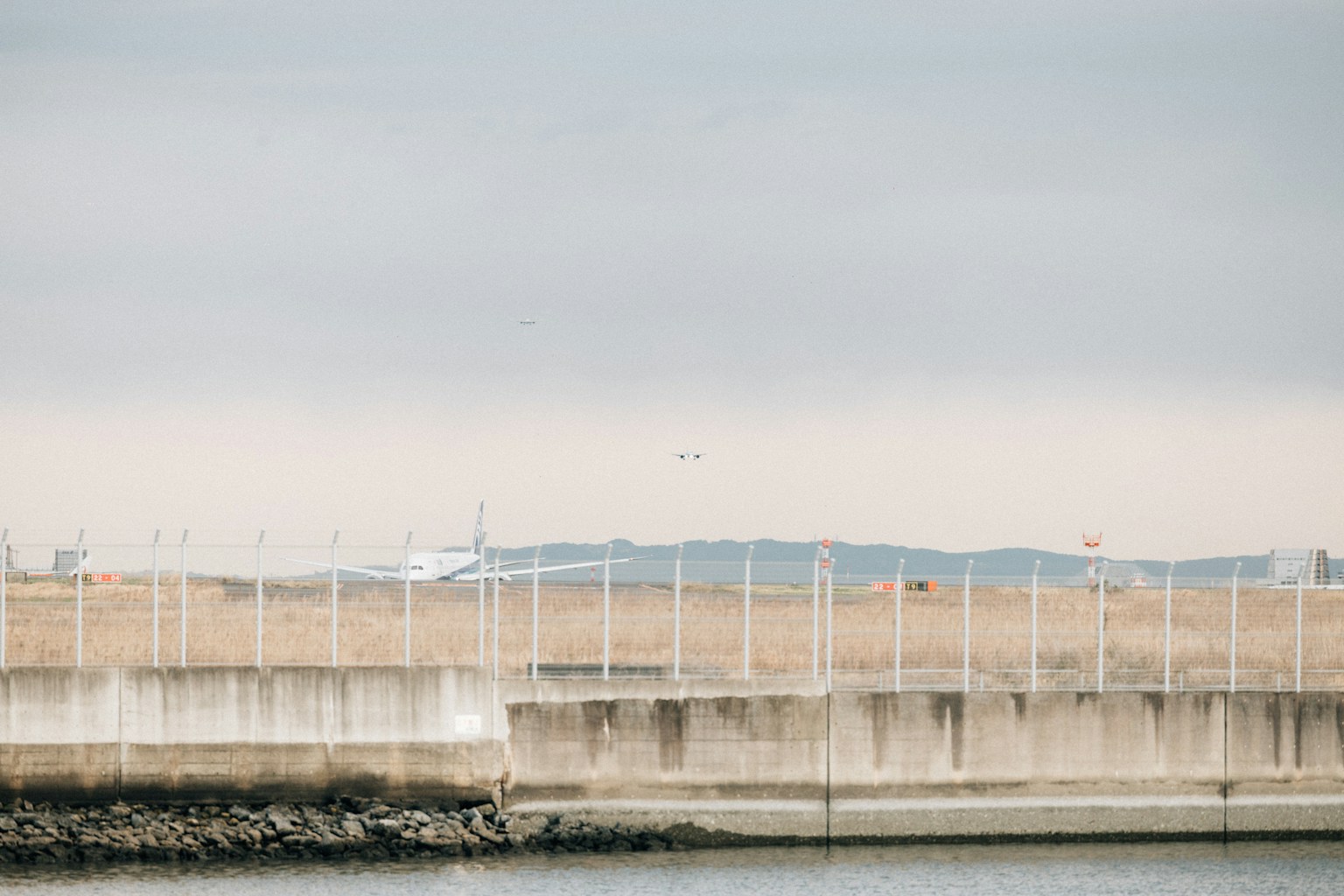 Airplane landing behind a low wall. (Photo by Tsuyoshi Kozu on Unsplash)