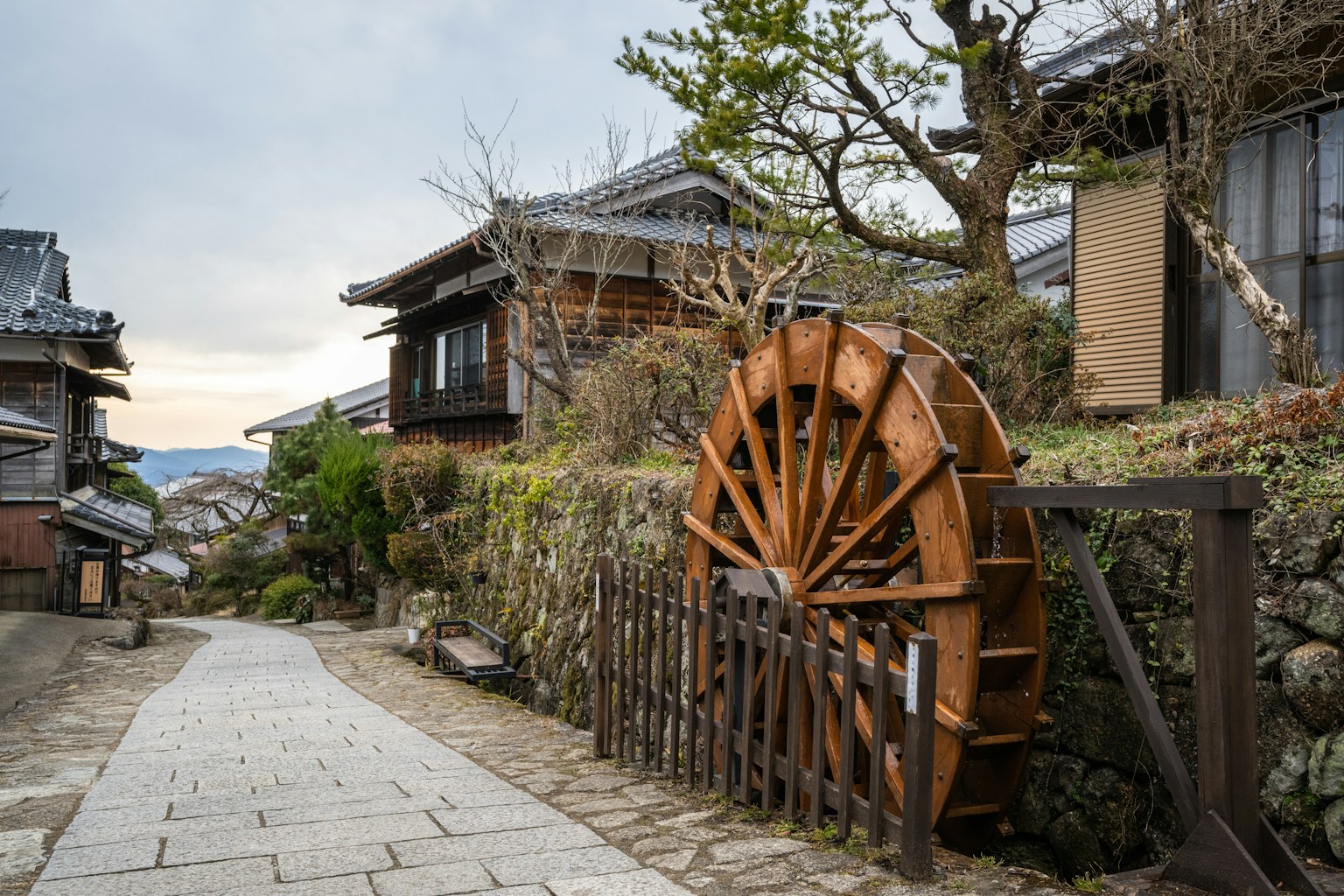 a wooden water wheel sitting on the side of a road (Photo by pen_ash on Unsplash)