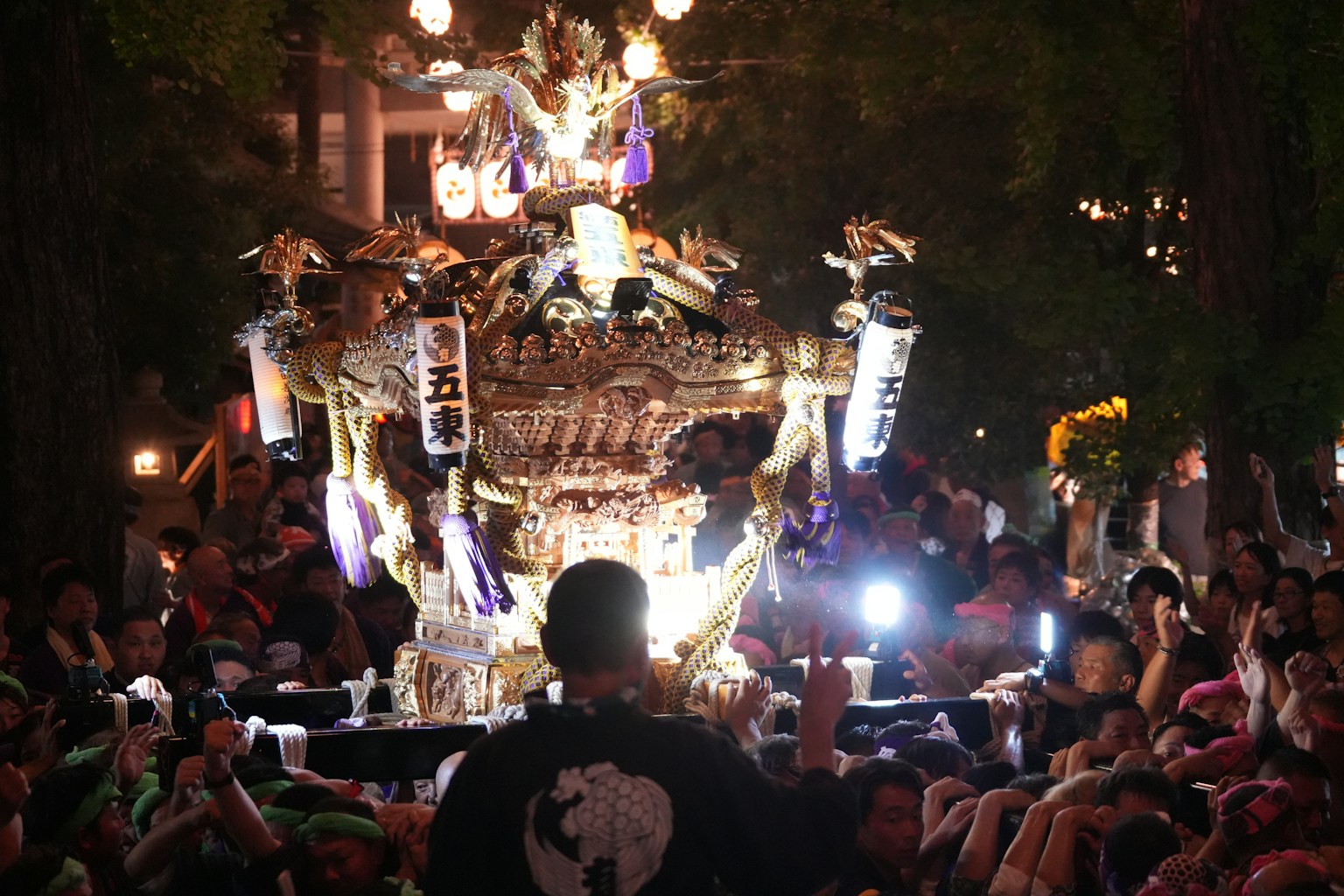 People carrying a large ornate float at night (Photo by Ryo Tanaka on Unsplash)