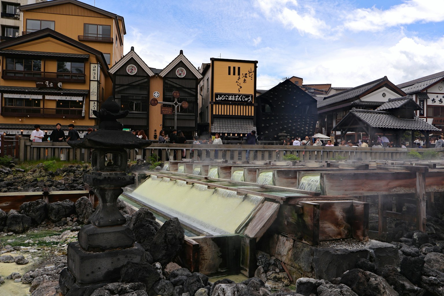 Steaming hot springs with traditional japanese buildings in background. (Photo by waa towaw on Unsplash)