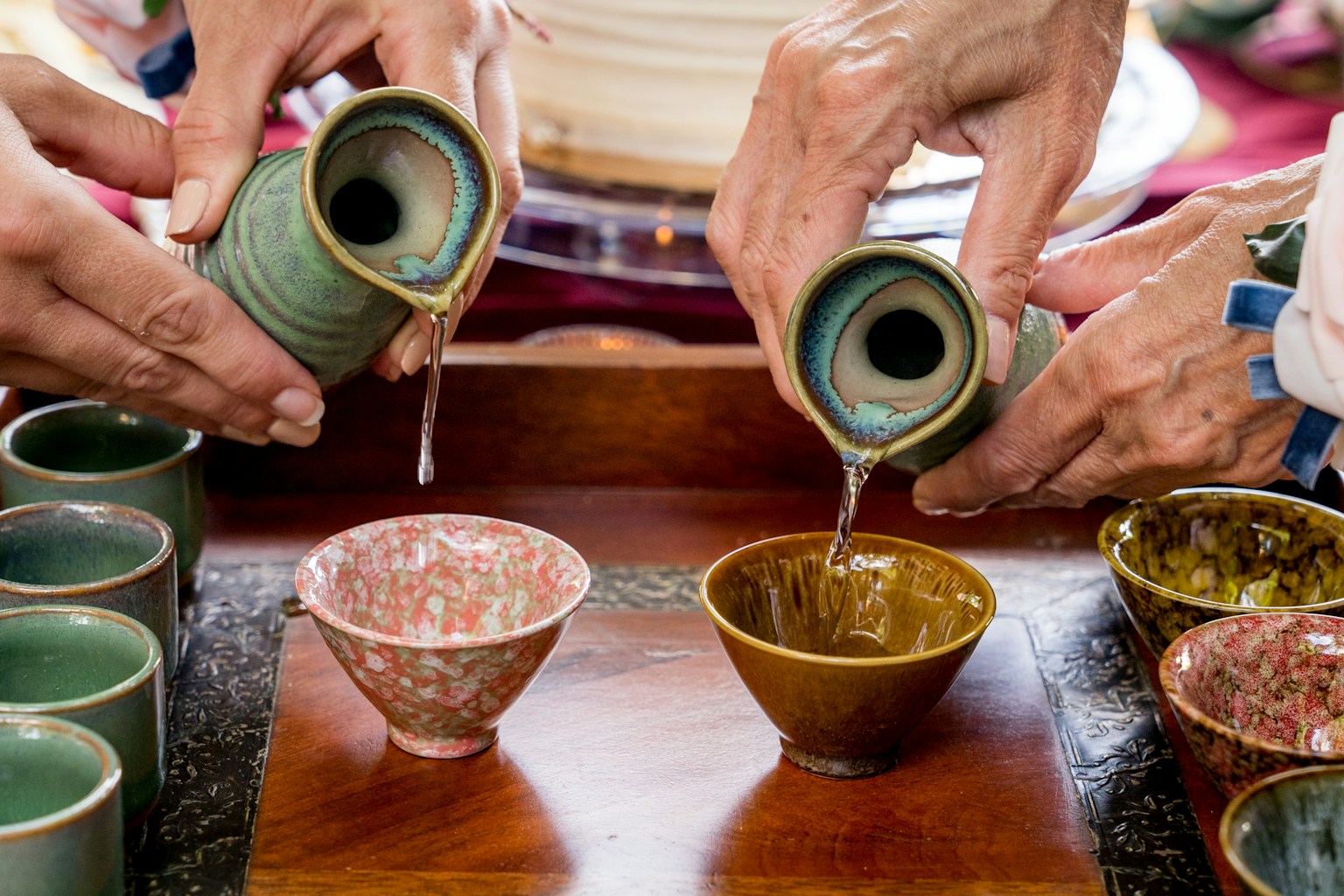a group of people pouring liquid into small cups (Photo by Frederick Shaw on Unsplash)