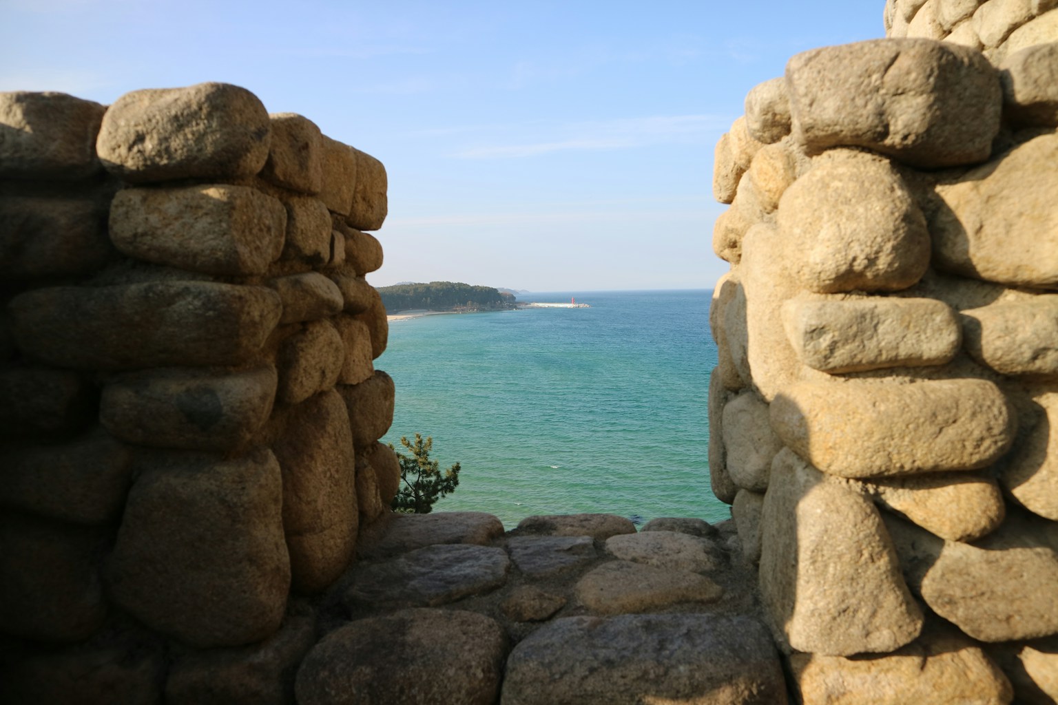 View of the ocean through stone walls (Photo by Jeong yunji on Unsplash)