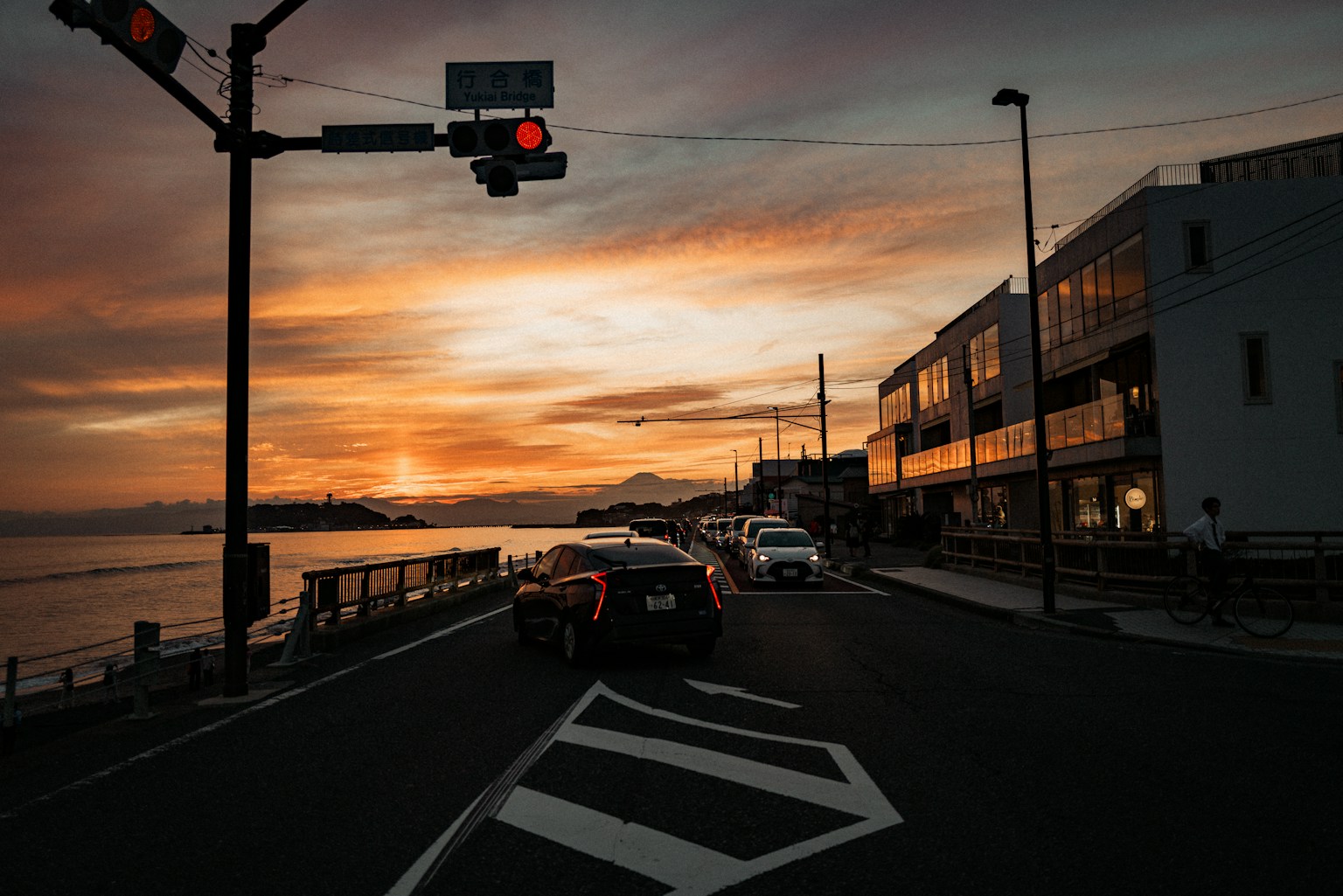 Cars on road during sunset with ocean view (Photo by Mario Scheibl on Unsplash)