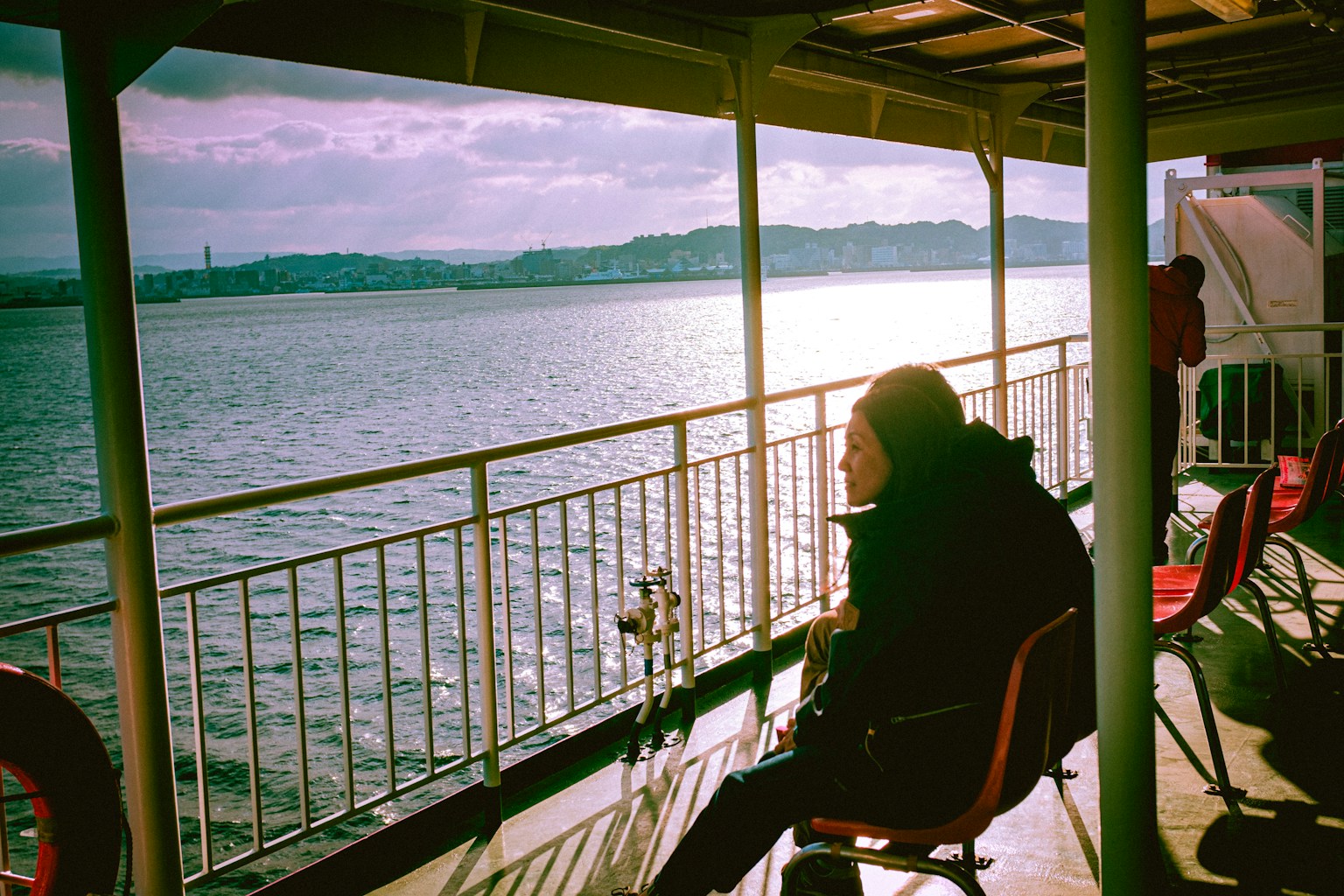 woman in black jacket sitting on chair near body of water during daytime (Photo by Christian Chen on Unsplash)