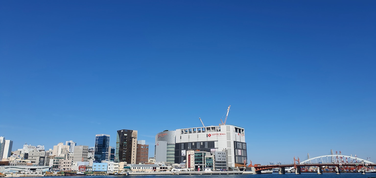 Modern cityscape with buildings and a bridge under blue sky. (Photo by New FLEX on Unsplash)