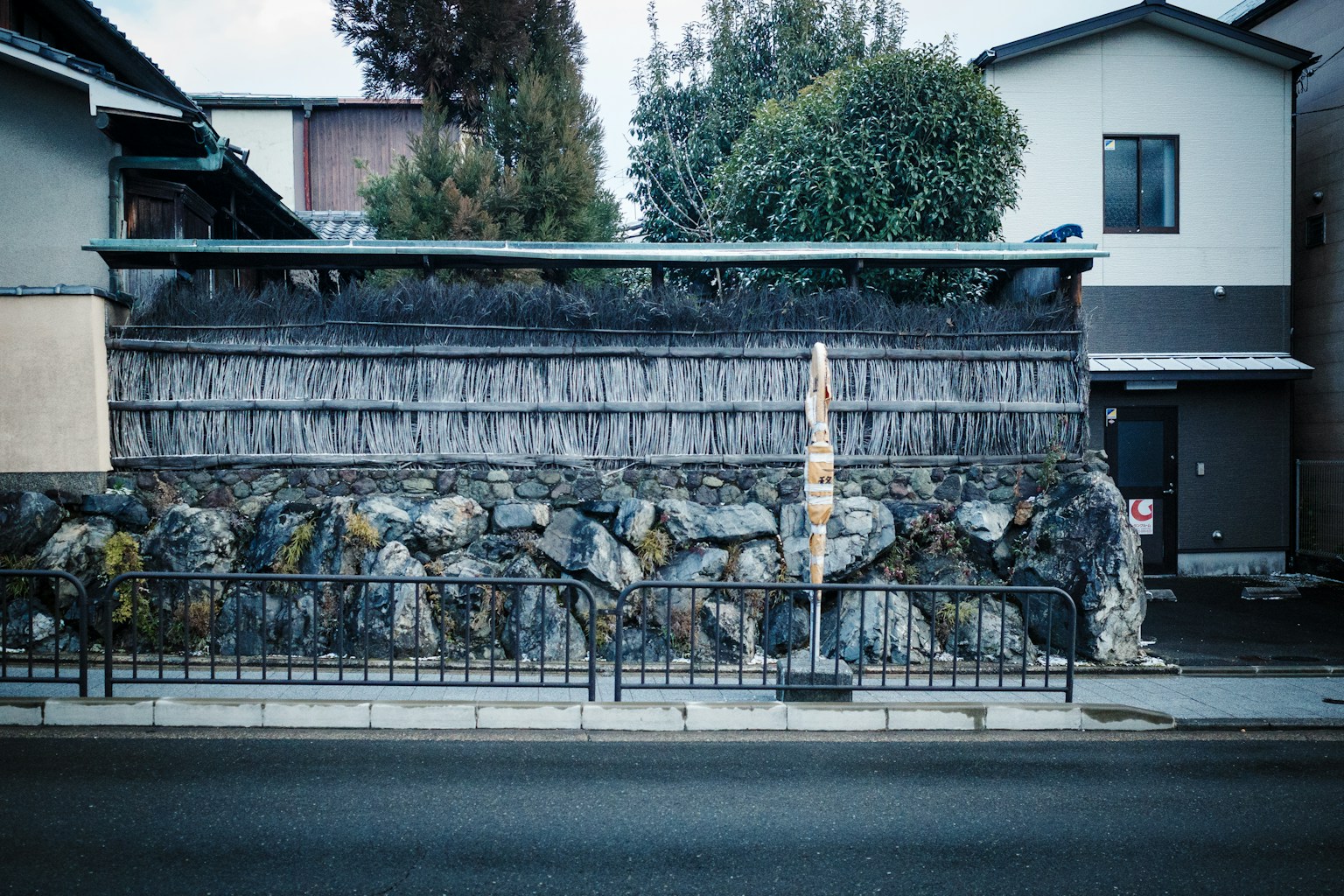 A stone wall with a wooden fence and street. (Photo by Leongsan on Unsplash)