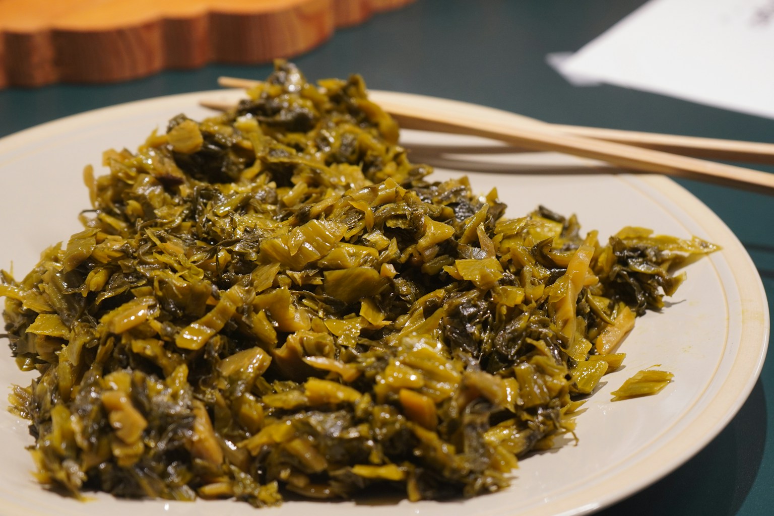 A plate of chopped pickled greens with chopsticks (Photo by Yosuke Ota on Unsplash)