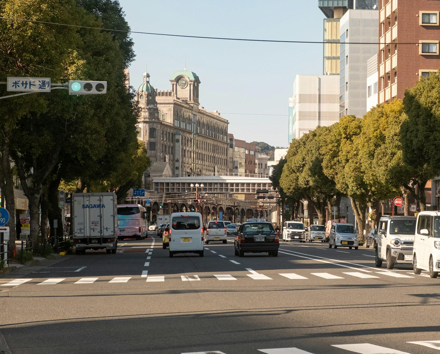 Cars driving down a tree-lined city street. (Photo by Tuan P. on Unsplash)