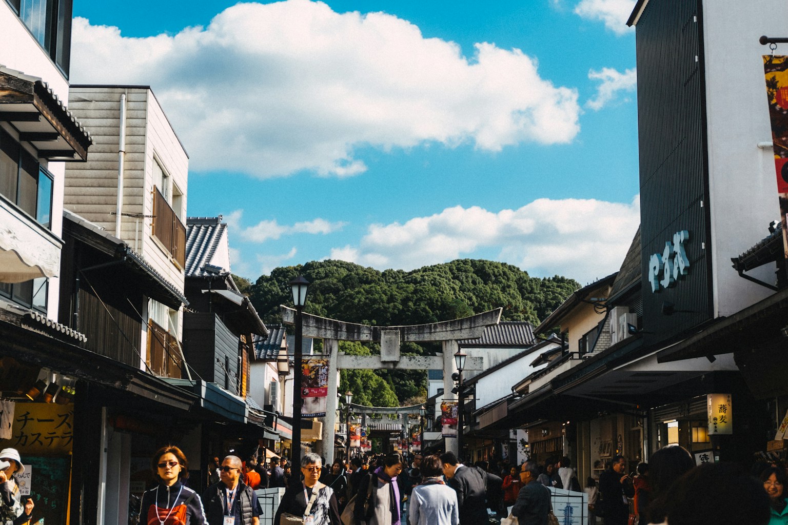 a group of people walking down a street next to tall buildings (Photo by Tayawee Supan on Unsplash)