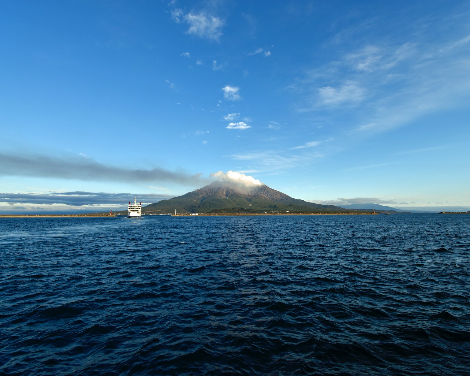a large body of water with a mountain in the background (Photo by Geoff Oliver on Unsplash)