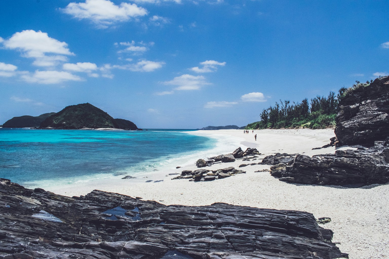 people walking in seashore near mountain (Photo by Roméo A. on Unsplash)