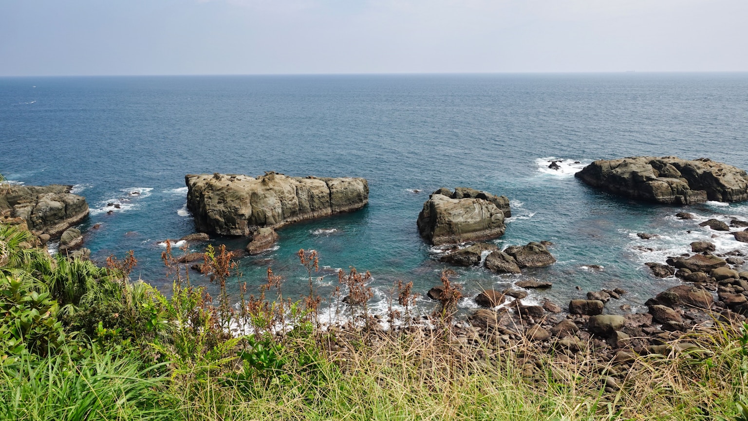 a body of water surrounded by rocks and grass (Photo by Winged Jedi on Unsplash)