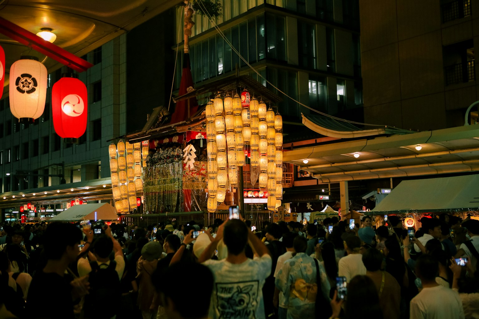 A crowd of people standing around a building at night (Photo by HANVIN CHEONG on Unsplash)